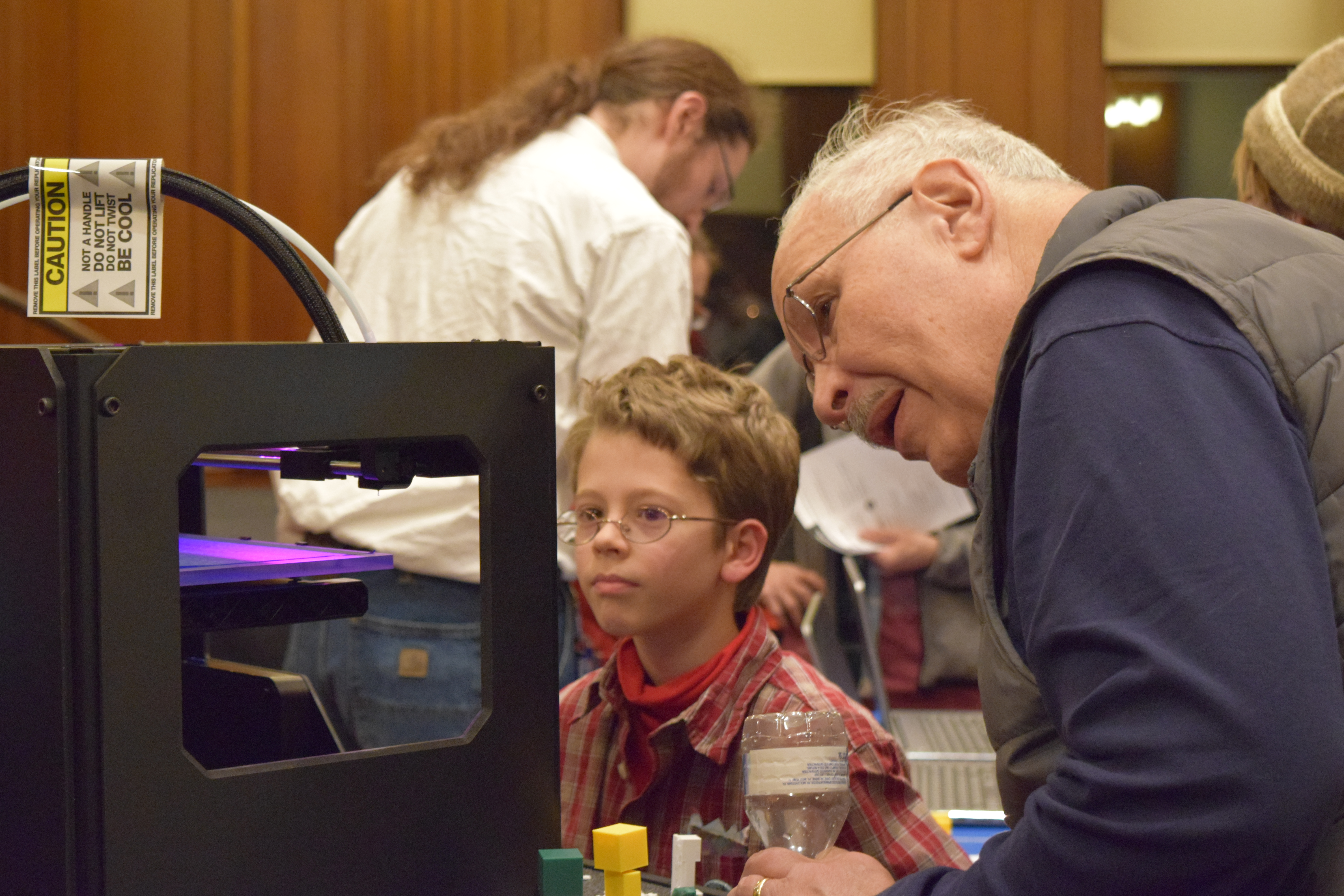 Picture of two people looking at a 3D printer